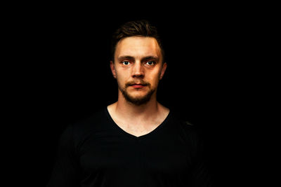 Portrait of young man against black background