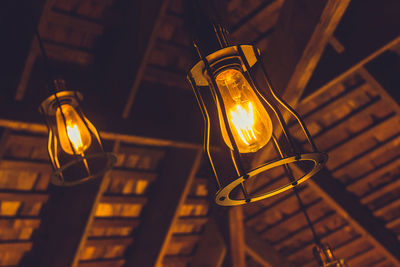 Low angle view of illuminated light bulbs hanging from ceiling