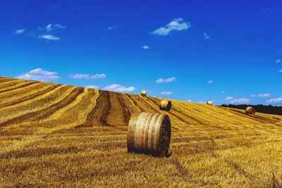 Hay bales on field against sky