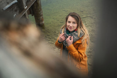 Portrait of smiling woman standing at lakeshore