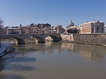 Bridge over river in city against clear sky