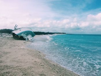 Broken ship at beach against sky