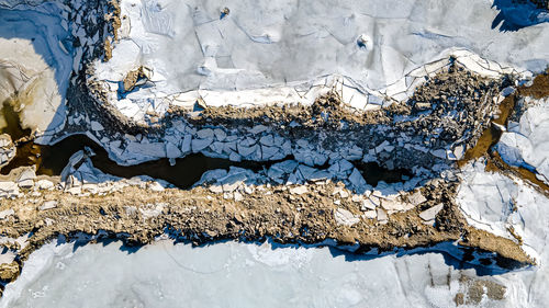 The ice has broken as snow melts at the quarry forming a small stream in the dirt.