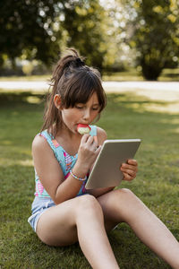 Girl on lawn using digital tablet