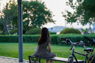 Rear view of woman sitting on bench in park