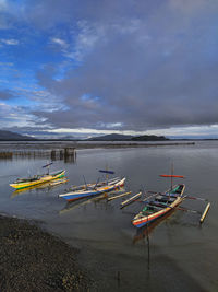 Fishing boats moored on sea against sky