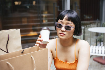 Lesbian woman holding disposable coffee cup sitting at cafe