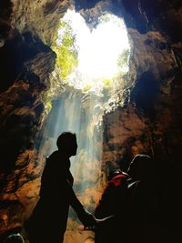 Silhouette man standing on rock in cave