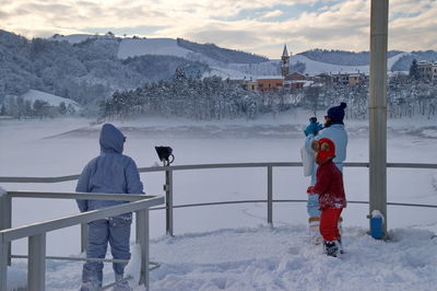 Rear view of people standing on snowcapped mountain