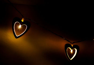 Low angle view of illuminated lights hanging against wall