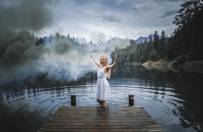 Woman standing by lake against sky