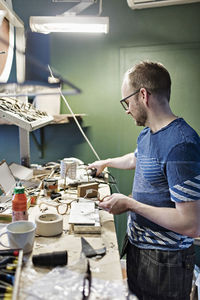 Side view of male owner working in eyewear workshop