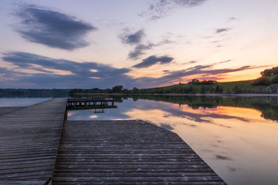 Pier over lake against sky during sunset