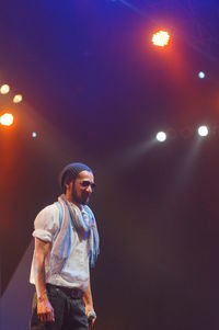 Full length of young man standing against illuminated lights at night