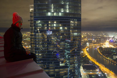 Man looking at illuminated city buildings at night