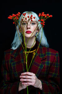 Portrait of woman with red flowers against black background