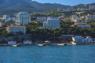 Scenic view of sea by townscape against mountain