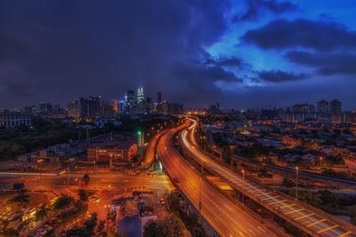 Light trails on road against cloudy sky