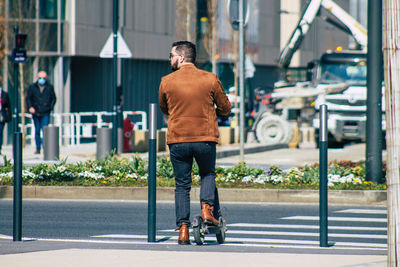 Rear view of man with umbrella on street in city