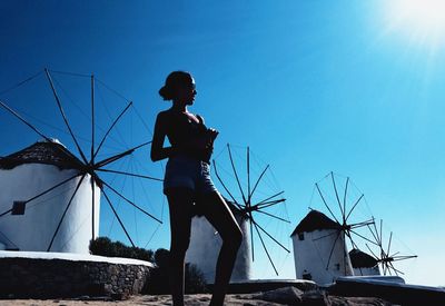 Woman standing against traditional windmills and blue sky