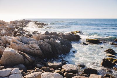 Rocks at beach against clear sky