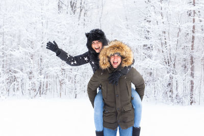 Happy young woman standing in snow