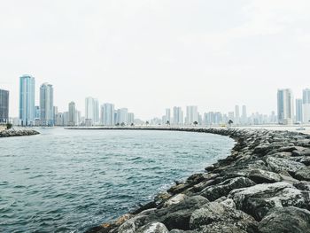 Sea by cityscape against clear sky