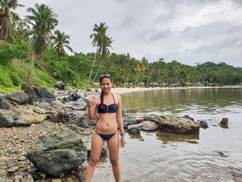 Portrait of young woman in bikini standing at beach