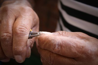 Cropped hands on man turning wire with tweezers