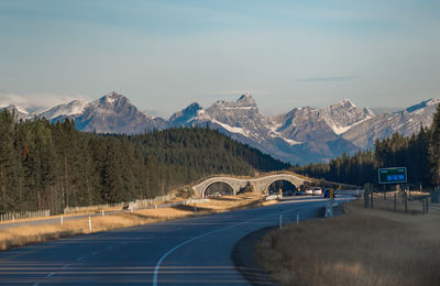 Road leading towards snowcapped mountains against sky