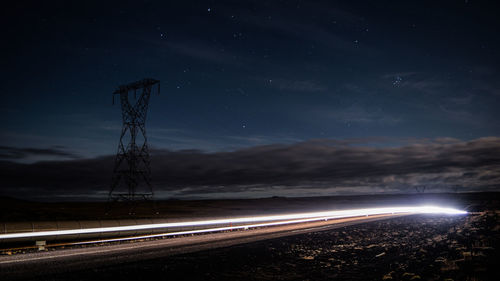 Light trails on road against sky at night