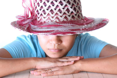 Close-up portrait of woman wearing hat against white background