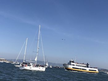 Sailboats sailing on sea against clear blue sky