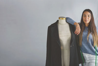 Portrait of young woman standing against white background