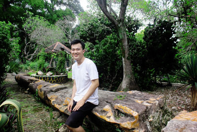 Portrait of smiling young man sitting on rock