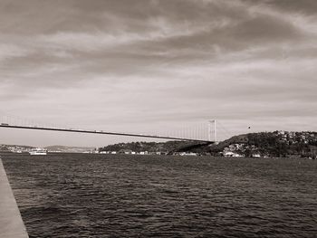 Bridge over river against cloudy sky