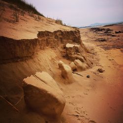 Rock formations on sand dunes at beach against sky