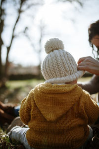 Mother and daughter wearing warm clothing while sitting on land