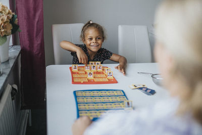 Happy girl playing game with mother at home