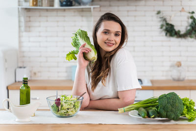 Portrait of young woman holding food at home