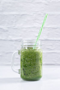 Green detox smoothie in a jar on white background. vertical format. healthy beverages concept.