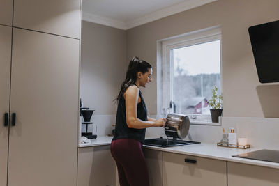 Woman washing dishes in kitchen