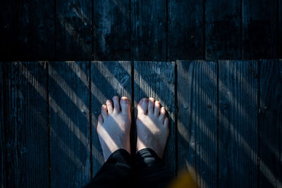 Looking down on bare feet standing on wood deck with lines of light