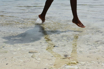 Low section of people running in water at beach