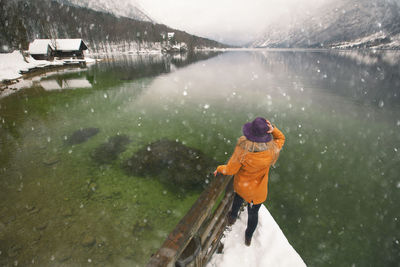 Rear view of woman on pier in lake during winter