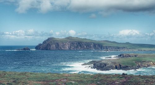 Scenic view of sea by mountains against sky