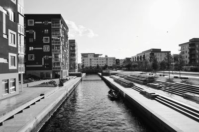 Canal amidst buildings in city against sky