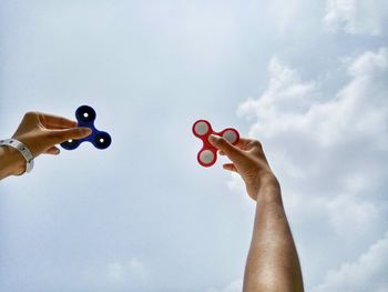 Low angle view of hands against sky