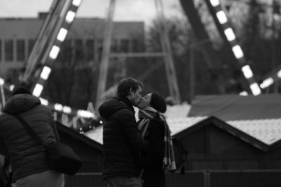 Side view of couple kissing while standing in city