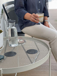 Midsection of man holding coffee cup on table